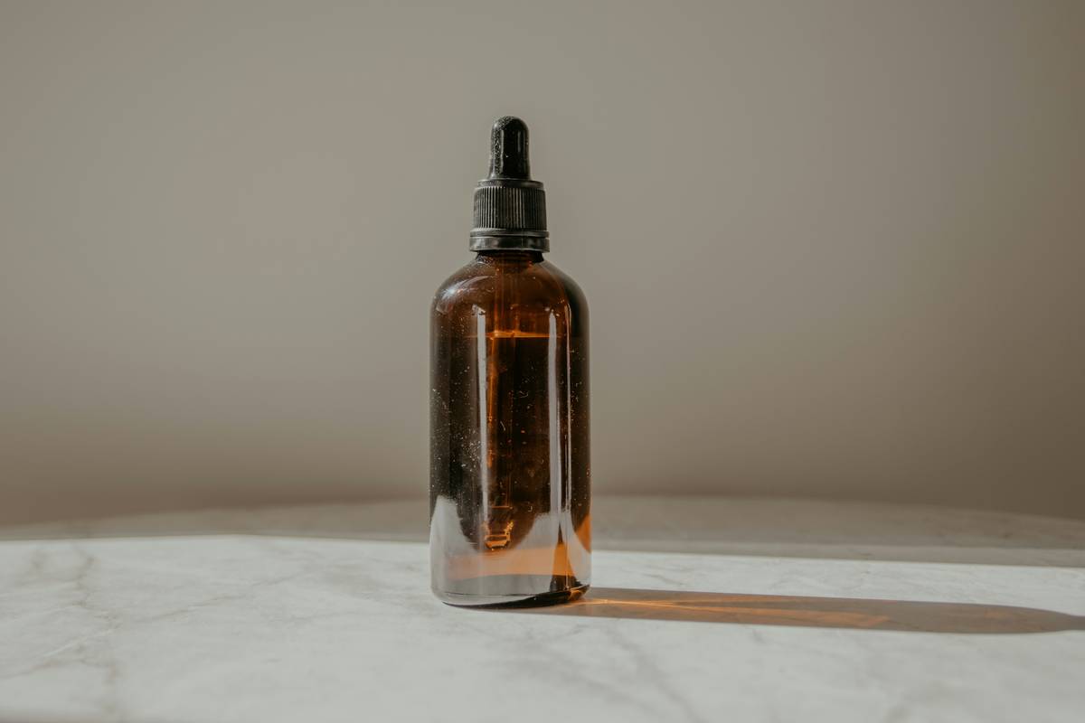 Step-by-step visual guide showing how to make scented oils with dark glass bottles and essential oils